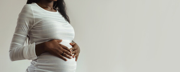 banner pregnant black woman in white clothes holds hands on belly on a white background. Pregnancy,...