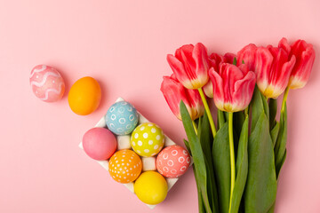 Easter eggs with a bouquet of tulips on a bright pink background. Easter celebration concept....