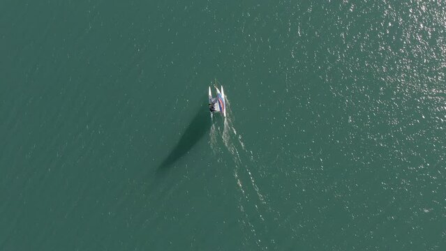 Top aerial view of a catamaran sailing alone on Lake Wanaka, New Zealand. Travel, freedom, and nature concept.
