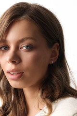 Obraz premium Beautiful young girl with fresh healthy skin. Woman advertise ear-rings. White background. Earrings closeup. Blond european woman with long hair with big lips, pretty smile. Cosmetology, scincare