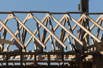 Obraz premium Close-up of wood roof trusses installed on a building under construction, showing framing structure used for supporting pitched roofs in residential or commercial development projects