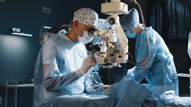 A surgeon looks through a microscope in the operating room. A doctor uses a microscope during eye surgery or diagnosis, cataract treatment and diopter correction.