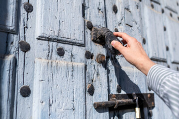 Closeup view of the hand of an unrecognizable man knocking on the wooden old door, male visitor...