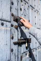 Closeup view of a man´s hand knocking on the wooden old door, male visitor standing in entrance, guest man wants to come in, he is using an iron knocker, free copy space