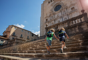 Two blond kids explore Girona, go up big stairs of Cathedral