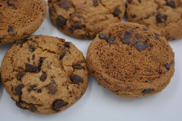 Sweets, delicious chocolate chip cookies with large chunks of milk and dark chocolate arranged on a white background.