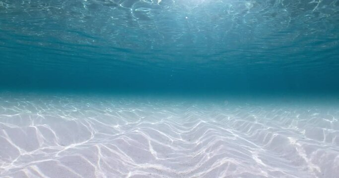 Transparent blue ocean with sandy bottom and waves underwater