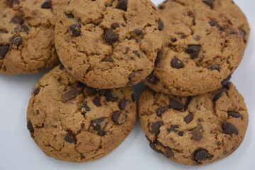 Sweets, delicious chocolate chip cookies with large chunks of milk and dark chocolate arranged on a white background.