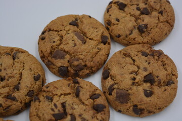 Sweets, delicious chocolate chip cookies with large chunks of milk and dark chocolate arranged on a white background.