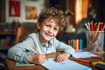 A young boy sitting at a table with a pencil and paper. Suitable for educational and creative concepts