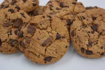Sweets, delicious chocolate chip cookies with large chunks of milk and dark chocolate arranged on a white background.