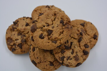 Sweets, delicious chocolate chip cookies with large chunks of milk and dark chocolate arranged on a white background.