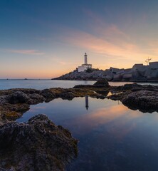 Fototapeta na wymiar landscape view of the Botafoc Lighthouse in Ibiza Town Port at sunsetwith reflections in tidal pools in the foreground