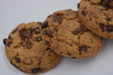 Sweets, delicious chocolate chip cookies with large chunks of milk and dark chocolate arranged on a white background.
