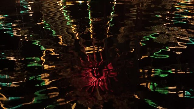 Reflection of the Ferris wheel lights in the water.