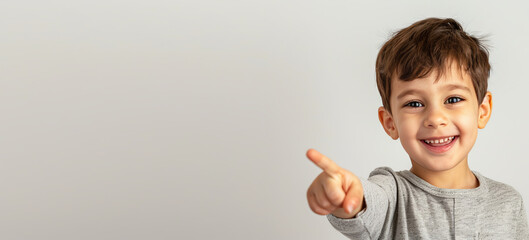 A little boy points his finger on an isolated light-colored background with free space generated AI