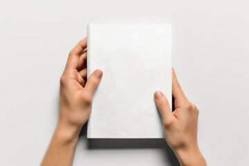 Obraz premium Person holding a white book, suitable for educational and reading concepts