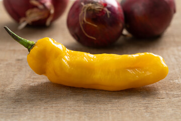 Whole fresh raw ripe yellow Madame Jeanette pepper close up on wood