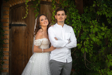 Wedding portrait of a stylish groom and a young bride near old wooden door