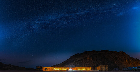 Scenic panorama of Milky Way dark night sky over tourists camp at Red Sea Hills mountain, Sahara...
