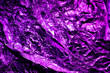 Purple and white background made of aluminum foil lit by neon light in dark environment. Empty space for design, copy space. 