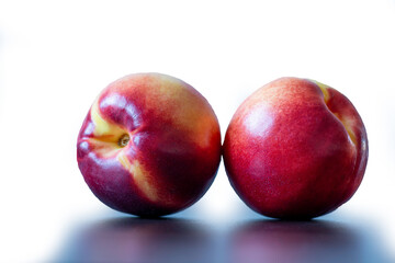 Pair of red yellow peaches white background, closeup view
