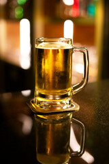 A mug beer on top of a rustic counter bar with light in background.
