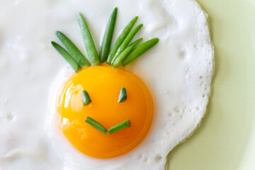 Funny fried egg with smiling smiley on plate, creative breakfast concept