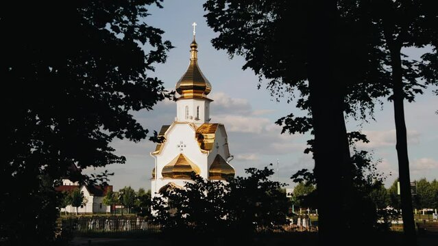 A large church with golden domes stands behind the trees. Smooth camera movement.