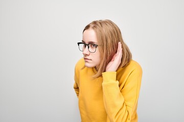 Portrait of girl eavesdropping, holding hand near ear isolated on white background