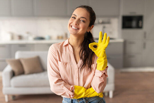 Smiling woman with yellow gloves giving okay sign