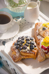 Morning breakfast with buns with cream, berries, fruits on a white tray. Breakfast in bed.