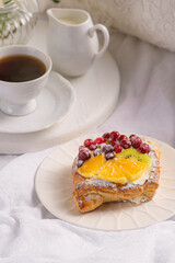 Morning breakfast with buns with cream, berries, fruits on a white tray. Breakfast in bed.