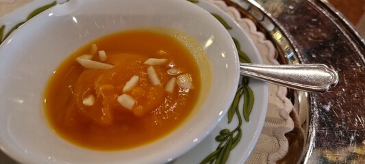 Bowl of creamy pumpkin soup garnished with almond slivers, ready to be enjoyed