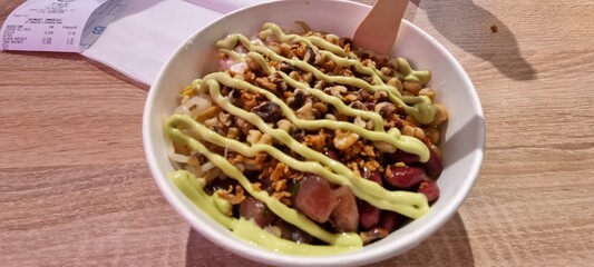 Flavorful rice bowl with mixed toppings and green sauce drizzled on top