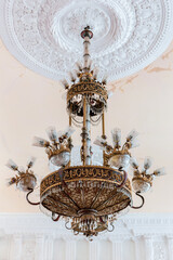 Old style vintage brass crystal chandelier in Niko Berdzenishvili Kutaisi State History Museum, main exhibition room, gypsum ornaments on the ceiling.