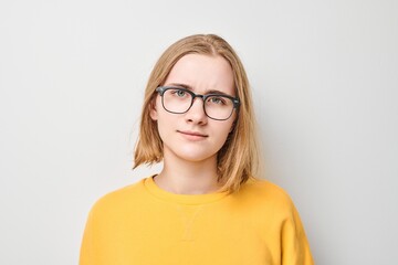 Portrait of girl with glasses wearing yellow top looking at the camera with neutral expression