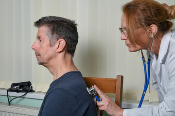Doctor examining a patient at an appointment. A female GP wearing a white coat checks her patient's...