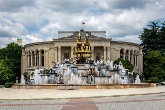 Colchis Fountain in Kutaisi, Georgia, modern fountain with golden statues of animals, replicas of ancient Georgian figures and Meskhishvili Theatre building in the background, symmetrical view