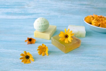 Soap with calendula, fresh flowers and useful plants, on a wooden background, natural cosmetics, body care and bath products
