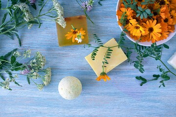 Soap with calendula, fresh flowers and useful plants, on a wooden background, natural cosmetics, body care and bath products