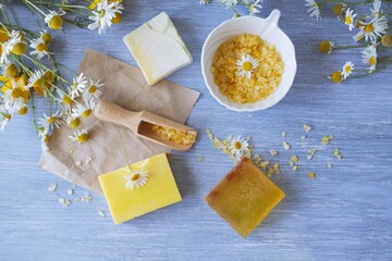 Soap with chamomile, bouquets of fresh chamomile flowers and sea salt, on a wooden background, natural cosmetics, body care and bath products
