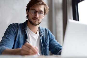 Businessman working with laptop from home sitting at table.