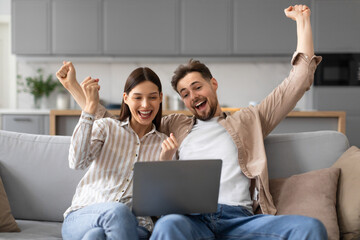 Overjoyed european couple celebrating with laptop, shouting yes