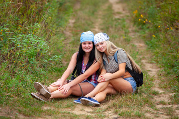 Happy couple of girls in bandanas on a rural road - 745237503