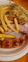 Delicious serving of bratwurst with sauerkraut and fries on a white plate