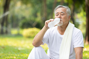 senior man drinking water after workout or exercising in the park