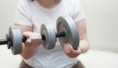 a close-up of women's hands is weighted by dumbbells made of plastic for sports and figure...