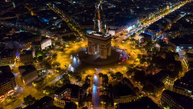 PARIS, FRANCE - FEBRUARY 20, 2024: Aerial drone timelapse motion hyperlapse view of the Arc de Triomphe (Triumphal Arch of the Star) with traffic on circle road. Famous monument at night from above.