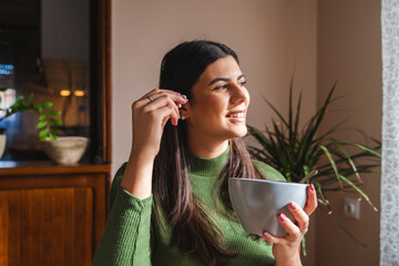 A young woman eating corn flakes for breakfast in the morning in her apartment	